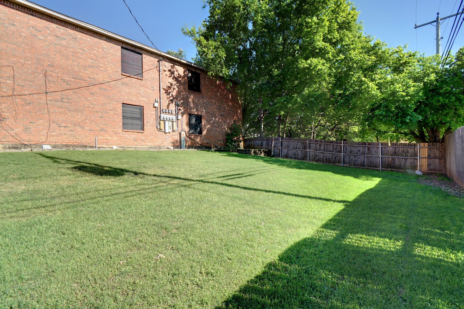 a yard with grass and trees in front of a brick building at The Chalk Gardens