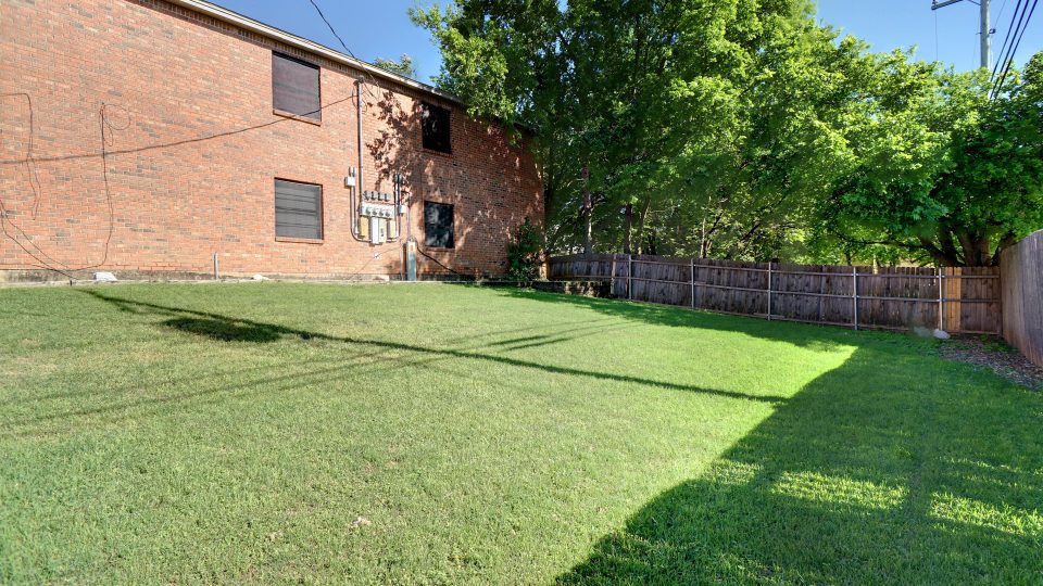 a yard with grass and trees in front of a brick building at The Chalk Gardens